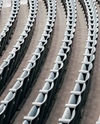 Schräg von oben aufgenommene Reihen leerer Opernsitze mit geschwungenen Armlehnen in der Oper Köln am Offenbachplatz. Die Sitze verlaufen in parallelen Linien und zeigen die klare Struktur und Anordnung des Zuschauerraums.