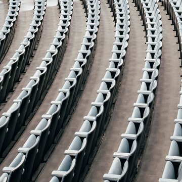 Schräg von oben aufgenommene Reihen leerer Opernsitze mit geschwungenen Armlehnen in der Oper Köln am Offenbachplatz. Die Sitze verlaufen in parallelen Linien und zeigen die klare Struktur und Anordnung des Zuschauerraums.