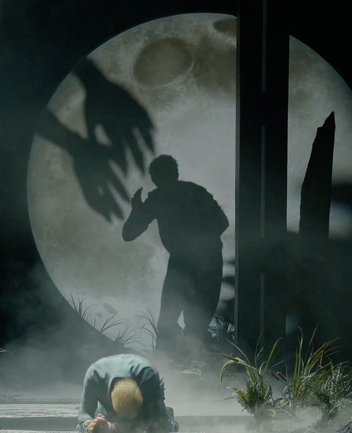 Siegmund kneels on the ground in exhaustion, while behind him the threatening silhouette of Hunding appears. His oversized shadow is cast against a huge full moon, stretching menacingly toward Siegmund. Fog, dark lighting, and sparse vegetation intensify the ominous atmosphere of this scene from Die Walküre by Richard Wagner.