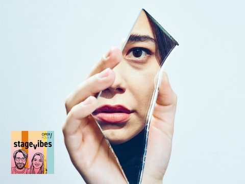 Eine Frau blickt durch eine zerbrochene Spiegelscherbe direkt in die Kamera. Das Motiv symbolisiert Zerbrechlichkeit, Verlust und Selbstsuche. Unten links befindet sich das farbige Visual des Oper-Köln-Podcasts Stagevibes.