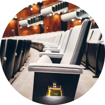 View of numerous evenly arranged rows of seats in the auditorium of the Cologne Opera at Offenbachplatz. The light-upholstered seats form a calm, geometric pattern and convey the size and order of the hall, with no people present.