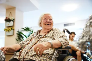 An older participant in a wheelchair smiles during an activity in the intergenerational project Unisono. The project creates opportunities for shared experiences, exchange, and creative participation among people of different generations.