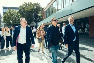 Oberbürgermeister Torsten Burmester sowie die Intendanten Kay Voges und Hein Mulders gehen gemeinsam über den Offenbachplatz vor dem Theatergebäude.