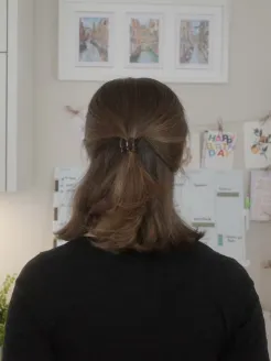 Giulia Montanari stands at home with her back to the camera, facing her wall calendar.