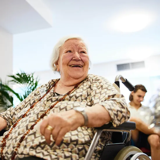 An older participant in a wheelchair smiles during an activity in the intergenerational project Unisono. The project creates opportunities for shared experiences, exchange, and creative participation among people of different generations.