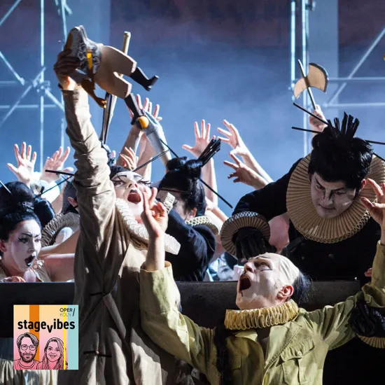 Scene from the opera Turandot: Several performers with white-painted faces and elaborate ruff collars move expressively across the stage. In the foreground, one person raises their arms with their mouth wide open, while other ensemble members gesture dramatically in the background. The scene is energetic and theatrical. In the lower left corner, the cover of StageVibes, the podcast of Oper Köln, is displayed.