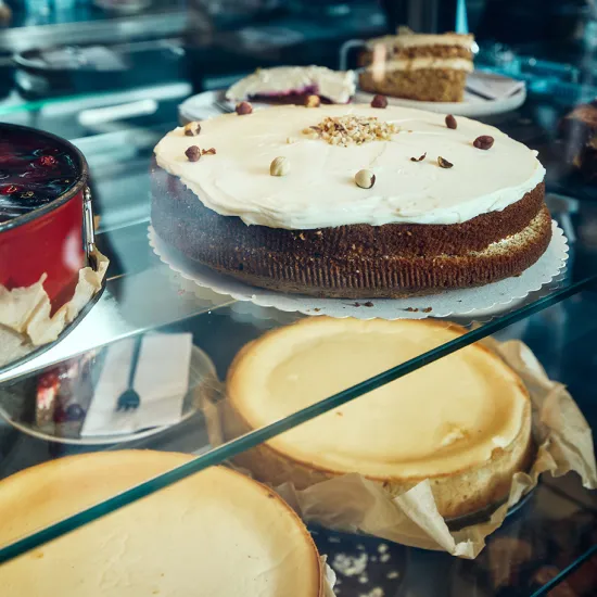 Nahaufnahme einer Auslage mit kleinen Kuchen. Die Speisen liegen in einer gläsernen Vitrine und vermitteln einen hochwertigen Eindruck des gastronomischen Angebots.