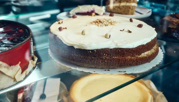 Nahaufnahme einer Auslage mit kleinen Kuchen. Die Speisen liegen in einer gläsernen Vitrine und vermitteln einen hochwertigen Eindruck des gastronomischen Angebots.